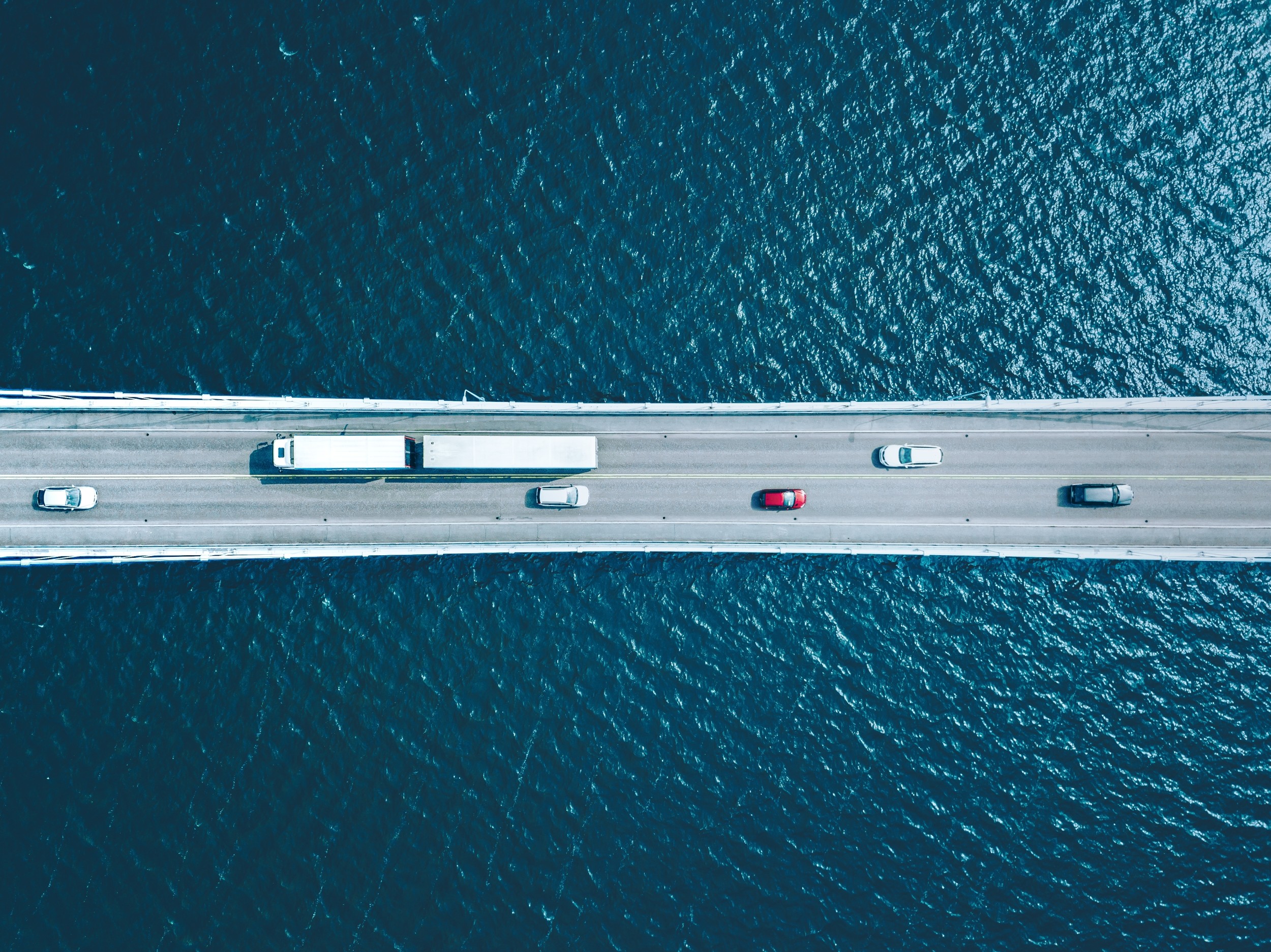 Autos und LKWs fahren auf einer Brücke über dem Meer