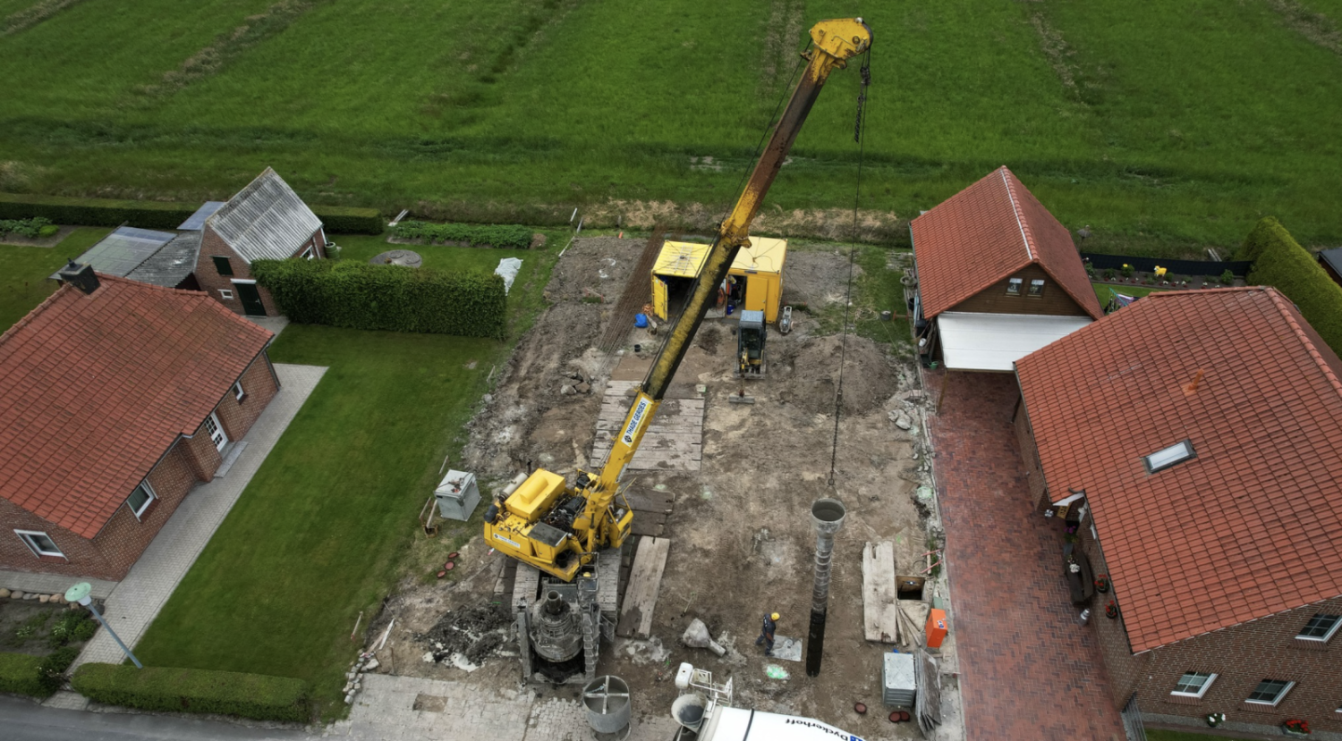 Luftaufnahme einer Baustelle zwischen Wohnhäusern, auf der eine Pfahlgründung hergestellt wird
